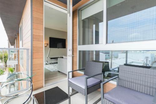 - Balcón con sillas de cristal y TV en un edificio en New Construction Modern Luxury Views Pool & Patio, en Los Ángeles