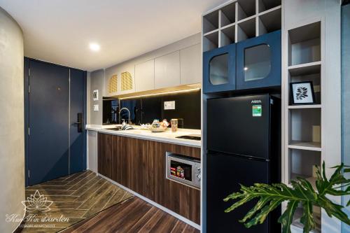 a kitchen with a black refrigerator and a sink at KunKin Garden Aparthotel in Ho Chi Minh City
