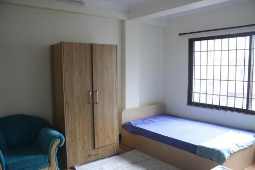 um quarto com uma cama, um armário e uma cadeira em Easyhome em Patan