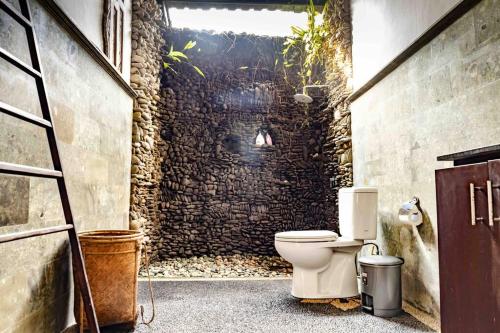 ein Bad mit einem WC in einer Ziegelwand in der Unterkunft Cultural Gem: 2bd Private Villa in Ubud