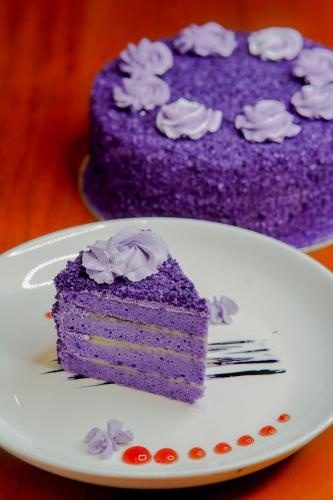 a piece of purple cake on a plate with a fork at Ragazzi Resort Hotel in Naga