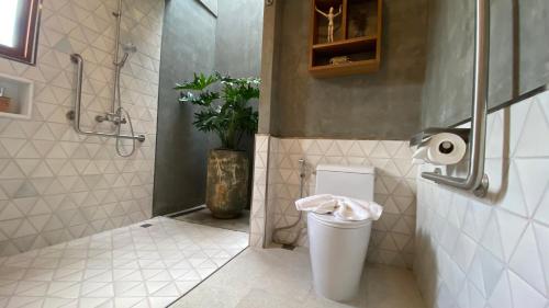 a bathroom with a toilet and a vase of flowers at Proud Phu Fah Muang Chiang Mai in Chiang Mai