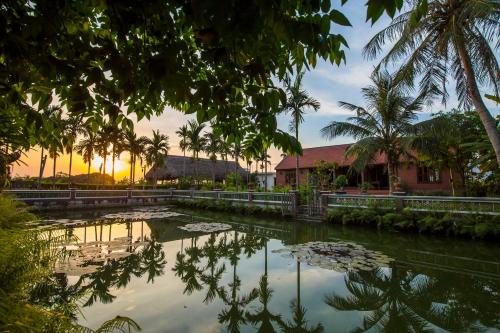 a pond in front of a house with palm trees at Viet House Yen Duc Village in Tử Lạc