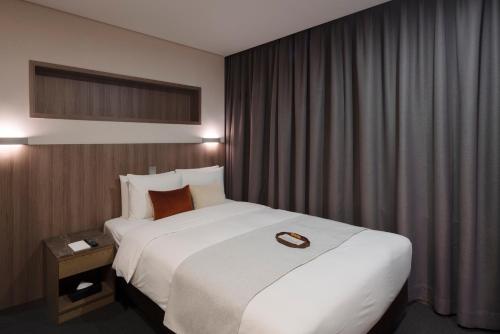 a hotel room with a large white bed and curtains at Amid Hotel Seoul in Seoul
