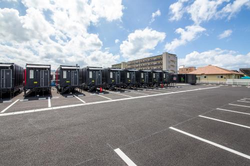 un estacionamiento con una fila de contenedores negros en HOTEL R9 The Yard Kirishimakokubu en Kirishima