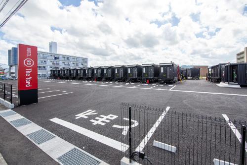 ein Parkplatz mit einer Reihe schwarzer Behälter in der Unterkunft HOTEL R9 The Yard Kirishimakokubu in Kirishima