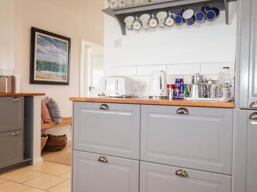 a kitchen with white cabinets and a counter at Cerrig in Holyhead
