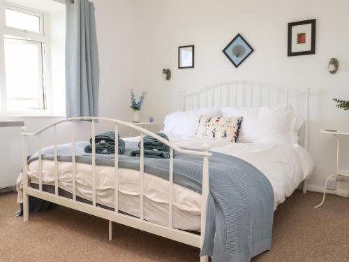 a bedroom with a white bed with a blanket on it at Cerrig in Holyhead
