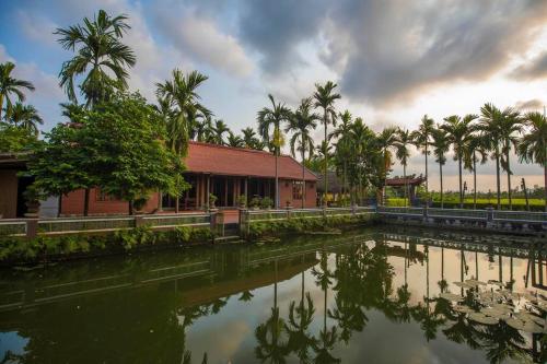 a building next to a body of water with palm trees at Viet House Yen Duc Village in Tử Lạc