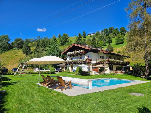 eine Villa mit einem Pool und einem Haus in der Unterkunft Pension Schnaitl in Maria Alm am Steinernen Meer