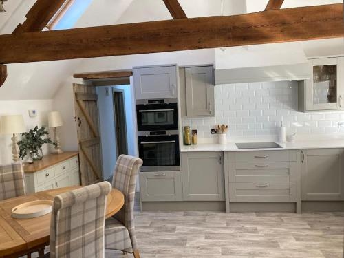 a kitchen with white cabinets and a wooden table at Spacious Cottage in Idyllic Spot in Fenny Compton