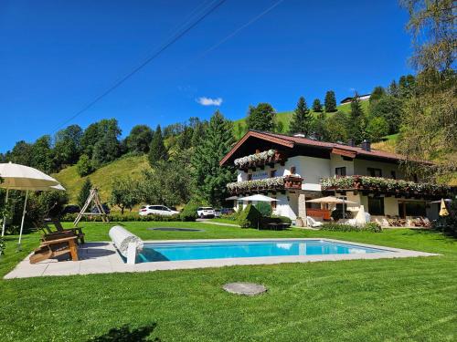 a villa with a swimming pool in front of a house at Pension Schnaitl in Maria Alm am Steinernen Meer