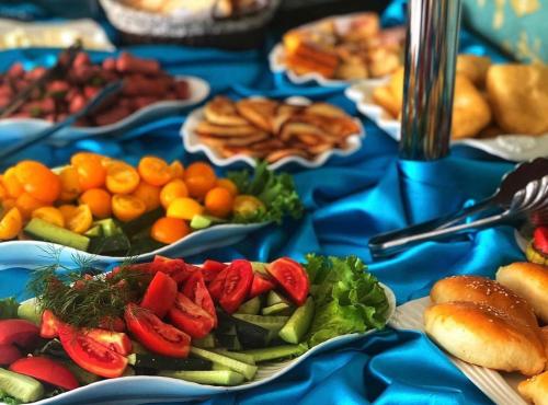 a blue table topped with plates of vegetables and fruit at Гостиничный комплекс Жеты Казына in Zharkent