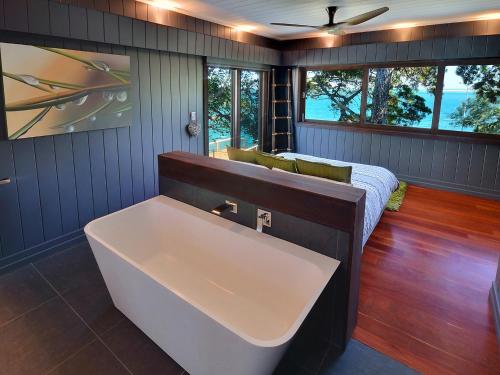 a bath tub in a room with a bed and windows at Dolphins at Sunset in Amity Point
