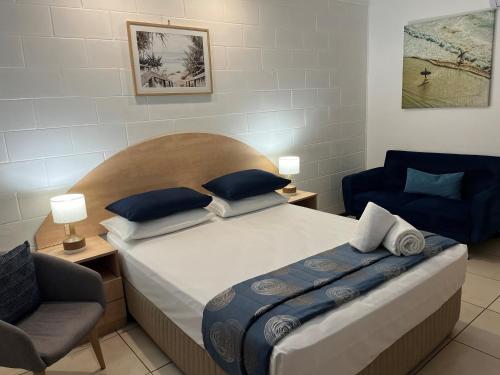 um quarto com uma cama grande e uma cadeira em Moffat Beach Motel Caloundra em Caloundra