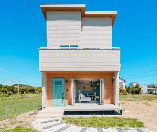 a house with a blue door on a beach at South coast Chikura in Chikura