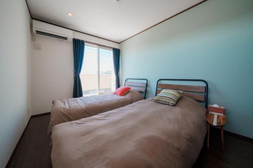 two beds in a small room with a window at South coast Chikura in Chikura