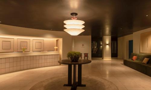 a lobby with a table and a large light fixture at Amid Hotel Seoul in Seoul