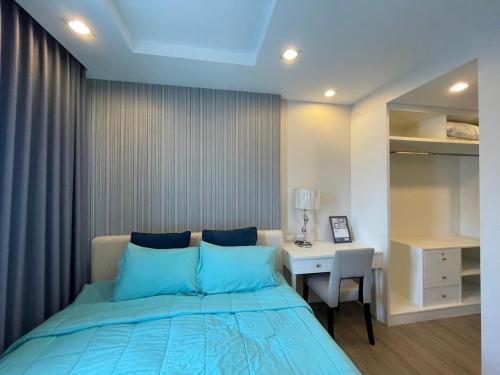 a bedroom with a bed with blue pillows and a desk at The Blu X Condo Bangsean R9 in Ban Bang Saen (1)