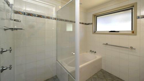 La salle de bains blanche est pourvue d'une baignoire et d'une douche. dans l'établissement Lentara Dream, à Fingal Bay