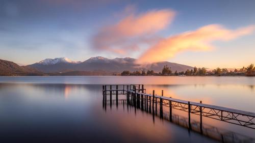 a dock on a lake with mountains in the background at Amber Court Motel in Te Anau