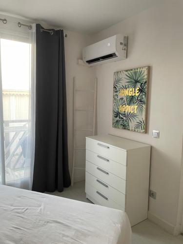 una camera da letto con un letto, una cassettiera e una finestra di Attrapes rêves a Saint-François