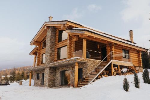 eine Blockhütte im Schnee mit einer Treppe in der Unterkunft CABANA CEITREI - MOUNTAIN VIEW GIUMALAU in Cozăneşti