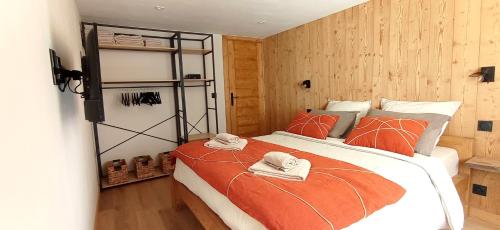 ein Schlafzimmer mit einem großen Bett mit orangefarbener Bettdecke in der Unterkunft *Spacieux T3 Campagne proche lac* in Magland