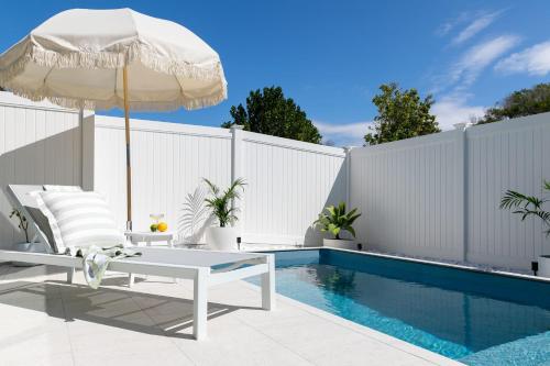 an umbrella and a chair next to a swimming pool at Yamba Beachside Escape - oceanstays in Yamba
