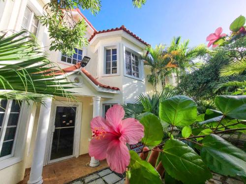 een roze bloem voor een wit huis bij Blue Heaven Guest House Bávaro, Punta Cana, Ideal For Couples in Punta Cana
