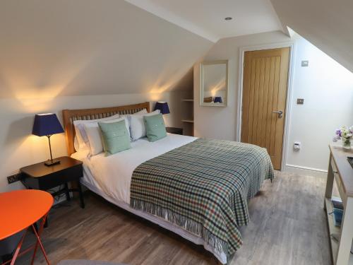 a bedroom with a large bed and a table with a lamp at Bay Tree Studio in Alnmouth