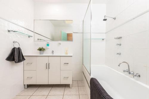 a white bathroom with a tub and a sink at Lazuli in Blueys Beach