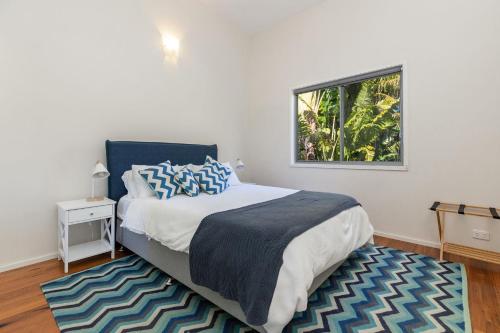 a bedroom with a bed with a window and a rug at Lazuli in Blueys Beach