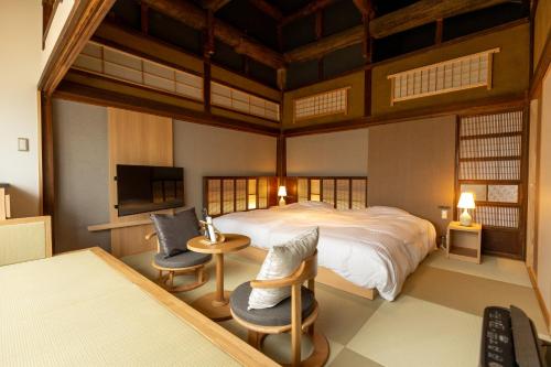 a bedroom with a large bed and two chairs at Classic ＆ modern SELF-STYLED HOTEL 番場おおそね in Chichibu