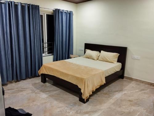 a bedroom with a large bed with blue curtains at High shine Homestay in Meppādi