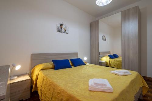 a bedroom with a bed with yellow sheets and blue pillows at Isola Rossa - Trilocale Grande in Isola Rossa