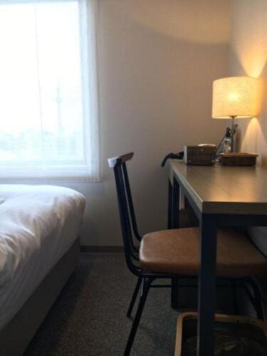 a bedroom with a desk with a bed and a lamp at ICI HOTEL Ueno Shin Okachimachi in Tokyo
