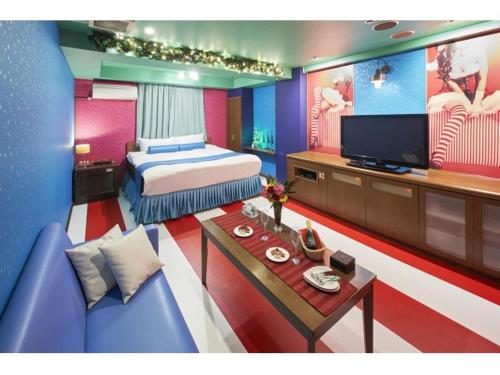 a bedroom with a bed and a tv and a couch at Hotel Chapel Christmas Narita -Adult Only in Narita
