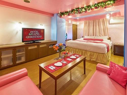 a hotel room with a bed and a couch and a table at Hotel Chapel Christmas Narita -Adult Only in Narita