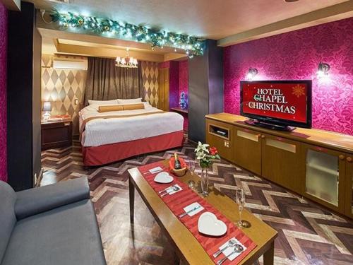 a hotel room with a king bed and a table at Hotel Chapel Christmas Narita -Adult Only in Narita