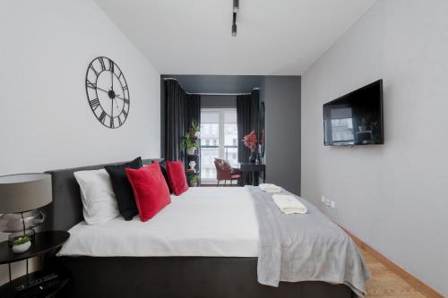 a bedroom with a large bed with red pillows and a clock at Lux Apartment with Parking, AC & Balcony on Kepa Mieszczanska by Renters Prestige in Wrocław