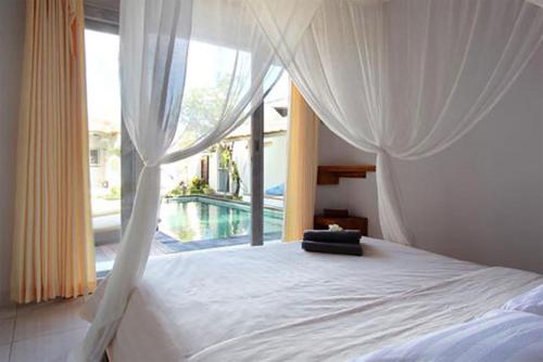 a bedroom with a canopy bed with a large window at Villa Noa by Optimum Bali Villas in Seminyak