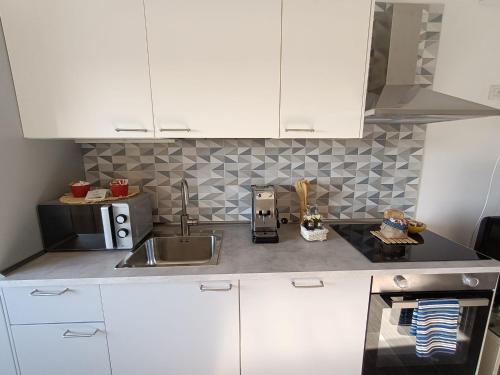 Una cocina con gabinetes blancos y un fregadero. en Appartamento Daisy - Parma, en Parma