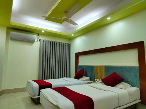 two beds in a bedroom with a ceiling at Wood Burn Hotel in Bogra