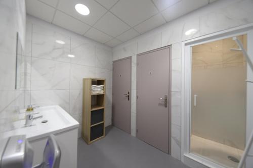 La salle de bains blanche est pourvue d'un lavabo et d'une douche. dans l'établissement Loft 250m2 avec écran led géant de 10m2, à Marseille