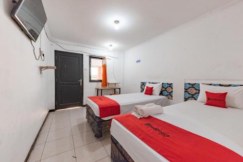 a room with two beds and a tv in it at RedDoorz Syariah At Cibadak Sukabumi in Sukabumi