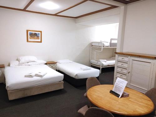 una habitación con dos camas y una mesa y sillas en Bathurst Explorers Motel, en Bathurst