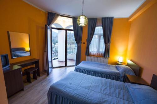 a bedroom with two beds and a desk and a mirror at Kris Hotel & Restaurant in Smolyan