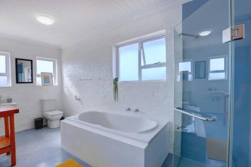 ein weißes Bad mit einer Badewanne und einem WC in der Unterkunft Jolie Beach Apartment in Wilderness