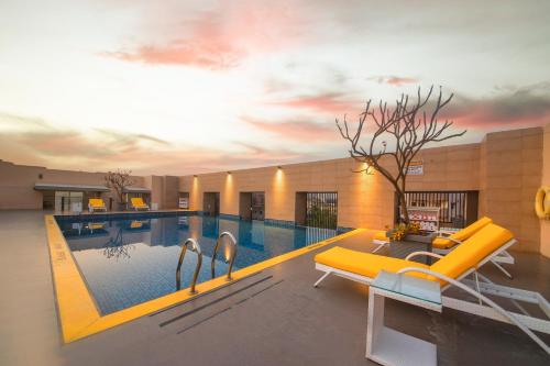 una piscina con un sofá amarillo y una mesa en Marigold Hotel en Hyderabad